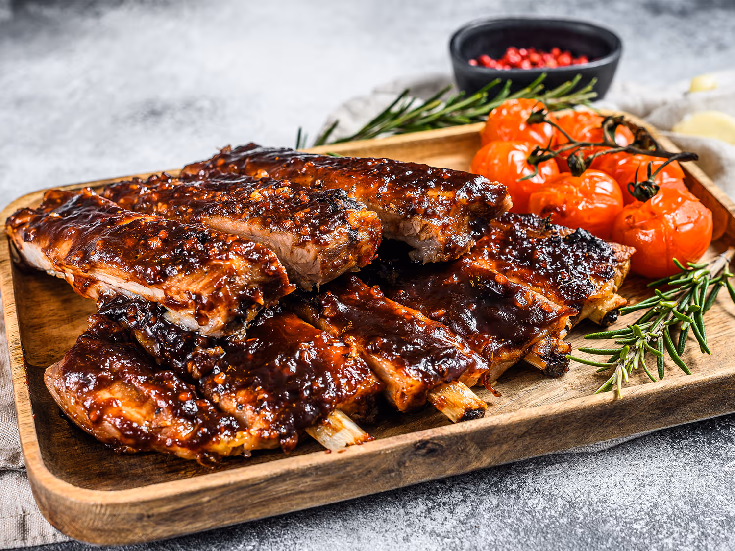 Des spareribs sur une assiette en bois avec des tomates