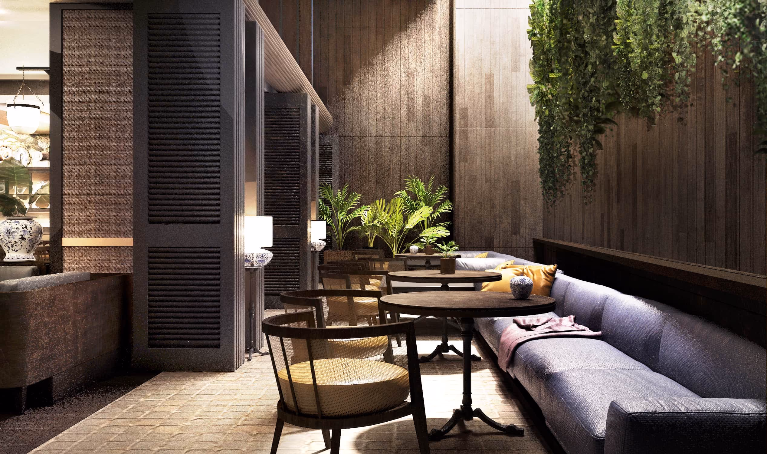 Cozy seating area with round tables, wooden chairs, long blue sofa, plants, and warm lighting.