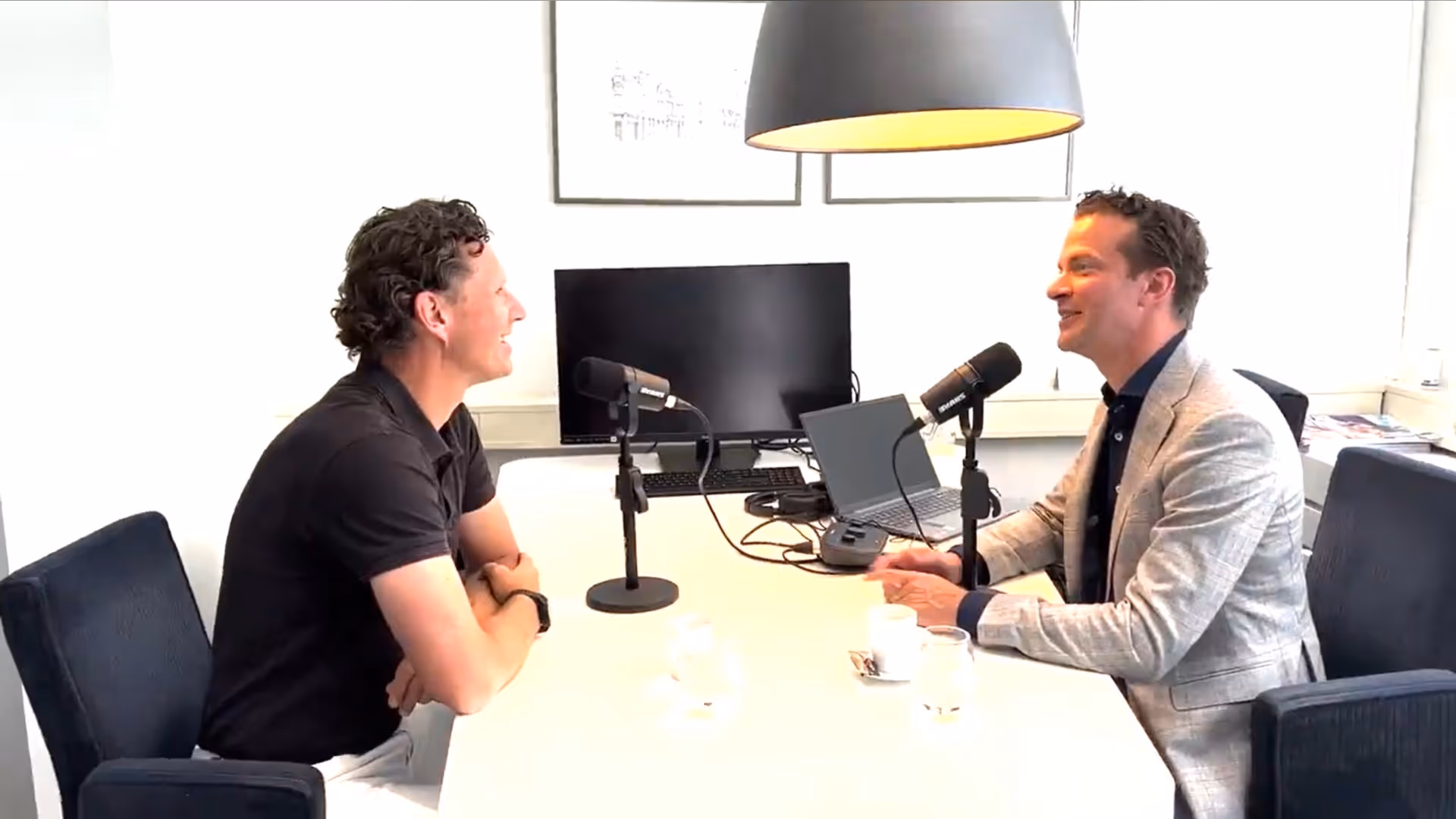 Twee mannen aan een tafel met beide een microfoon