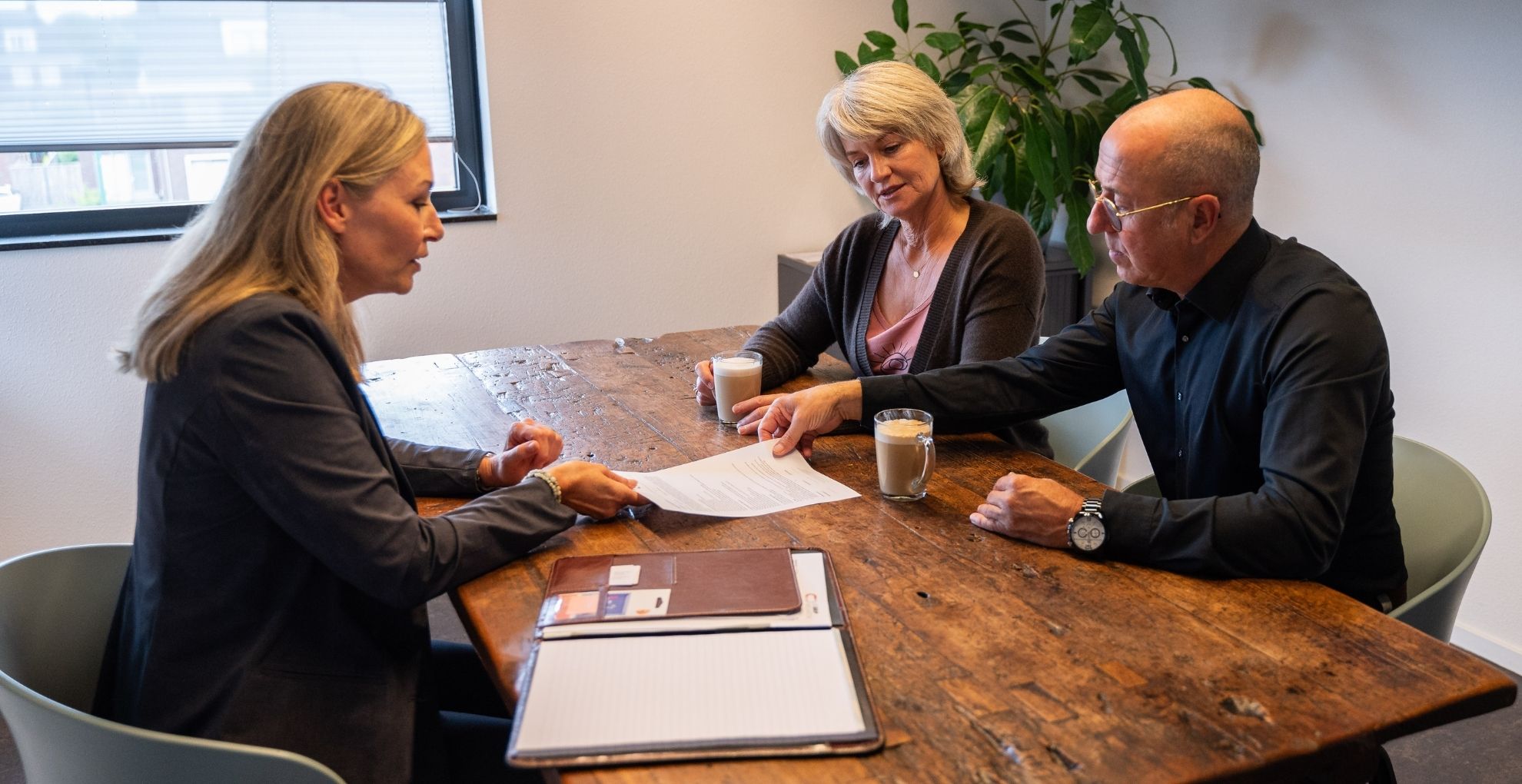 Drie personen in gesprek aan tafel