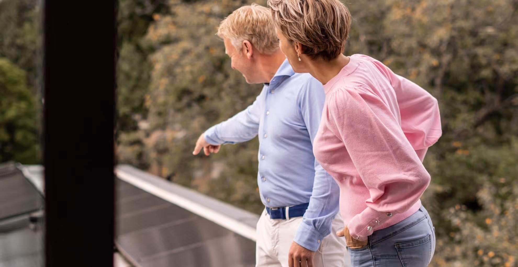 Two people on the roof with one pointing to solar panels