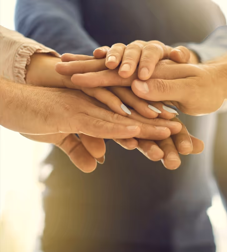 Meerdere handen op elkaar gestapeld, symboliseert samenwerking en eenheid.
