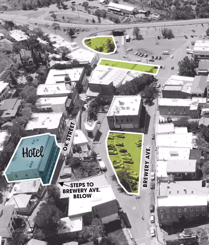 Aerial black-and-white view of a town highlighting a hotel building in blue and three parking areas in green near OK Street and Brewery Avenue with labeled steps to Brewery Ave.