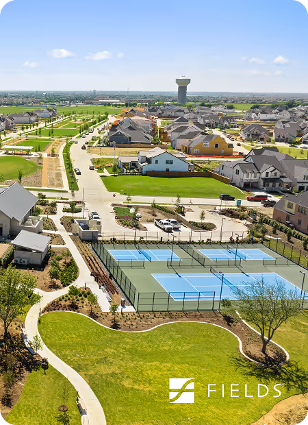 Suburban neighborhood with houses, green lawns, a water tower, and a fenced playground in the foreground.