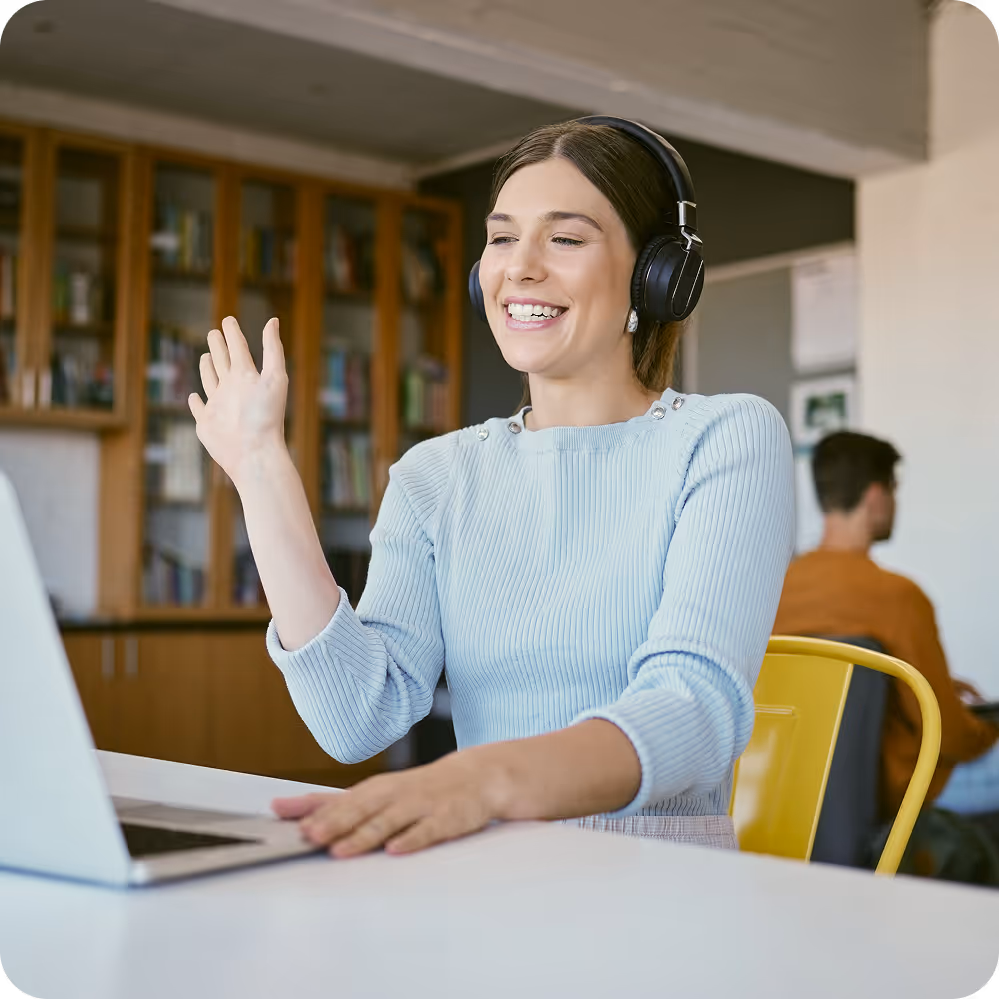 Woman smiling and waving while video chatting on a laptop