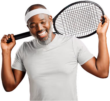 Smiling man holding a tennis racket over his shoulders on a black studio background.