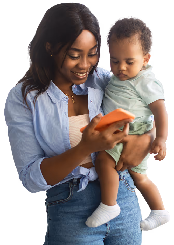 Smiling woman holding a baby while looking at a smartphone.