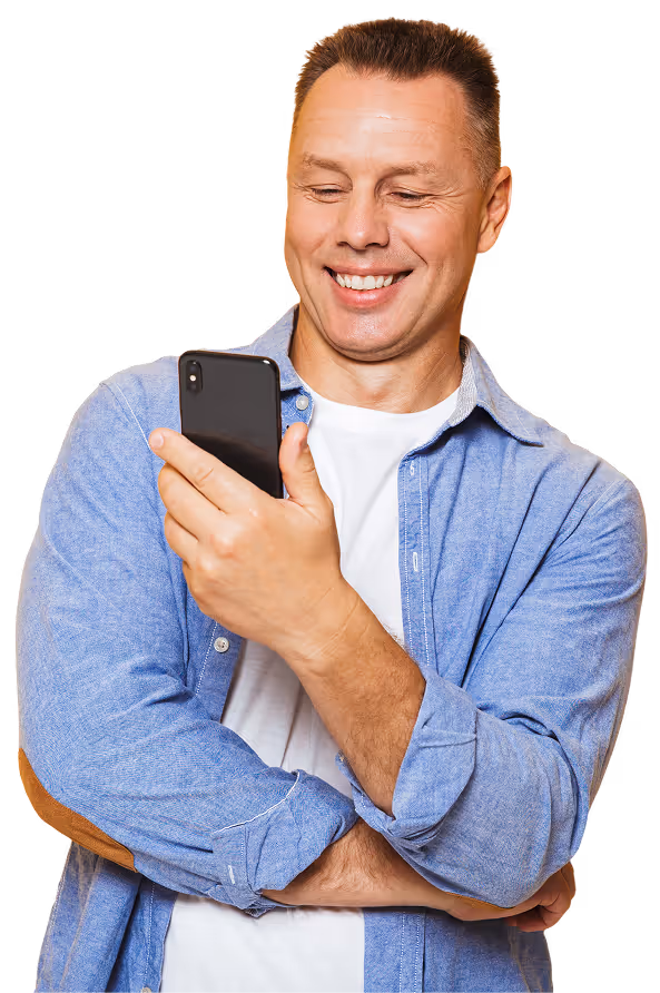 Smiling man in blue shirt looking at smartphone he holds in his right hand.