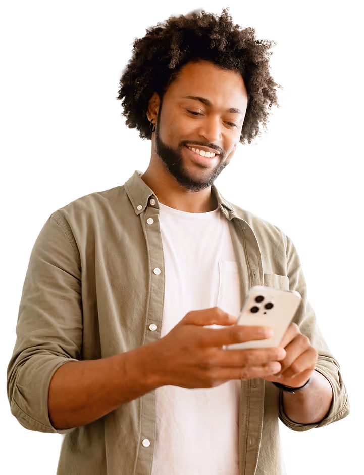 Smiling man with curly hair wearing a white shirt and green jacket using a smartphone.