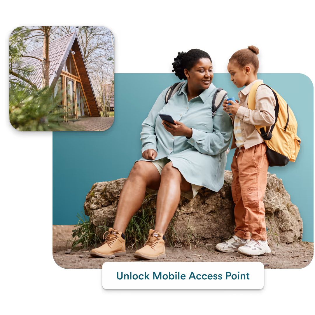 Mother sitting on a rock using a smartphone while her daughter with a backpack stands nearby drinking.