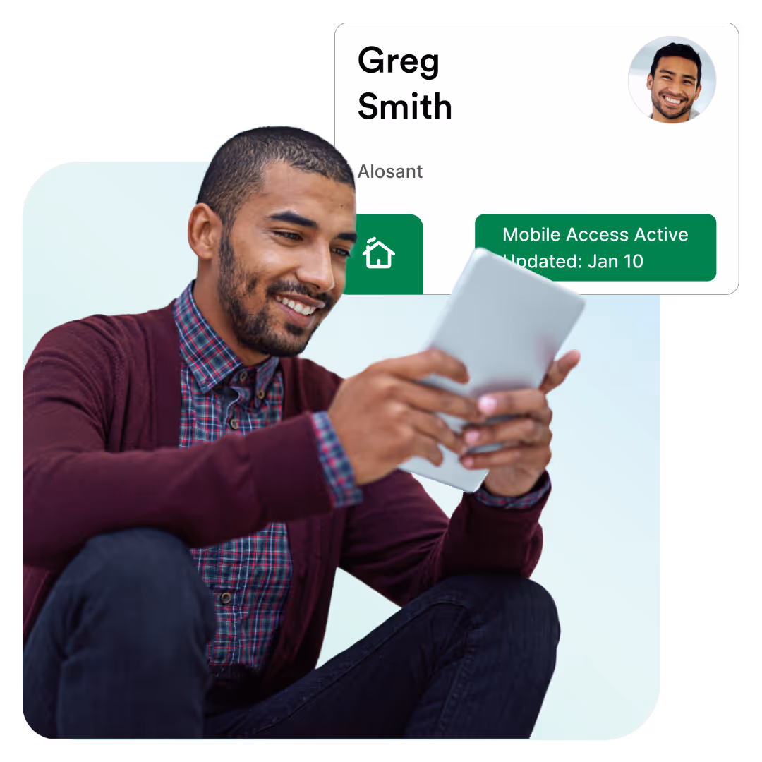 Smiling man sitting while holding and looking at a tablet device with a profile card overlay.