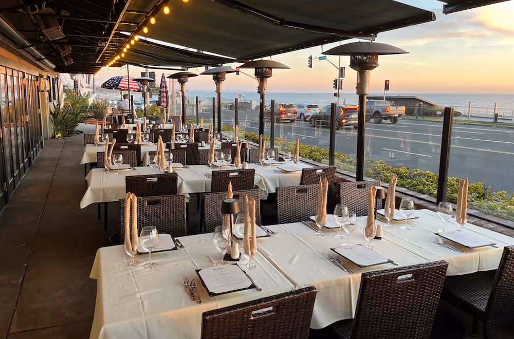 View of the ocean from a restaurant patio during sunset.