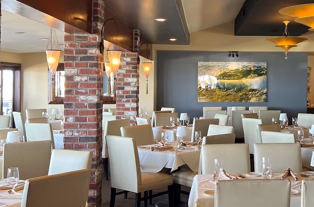 Indoor dining room at Vigilucci's Seafood and Steakhouse, with exposed brick and sunlight coming in from the windows.