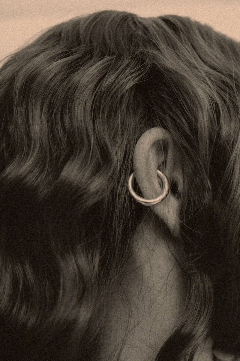 Wavy hair falling over a hoop earring, close up