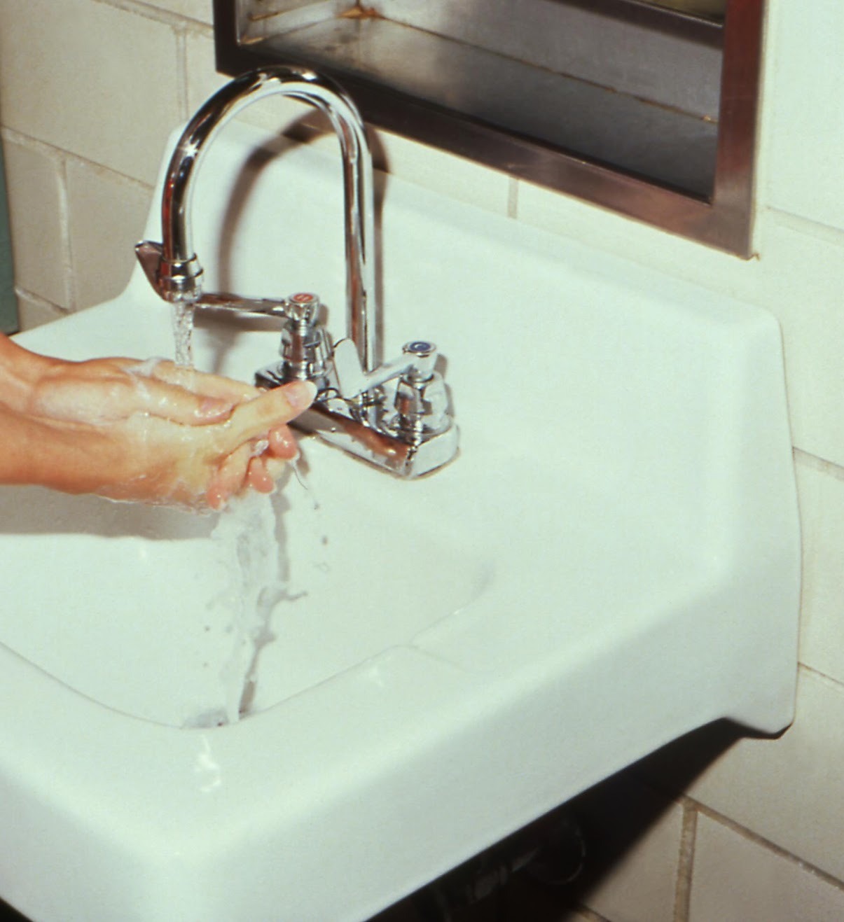 A hand under a running tap at a studio basin