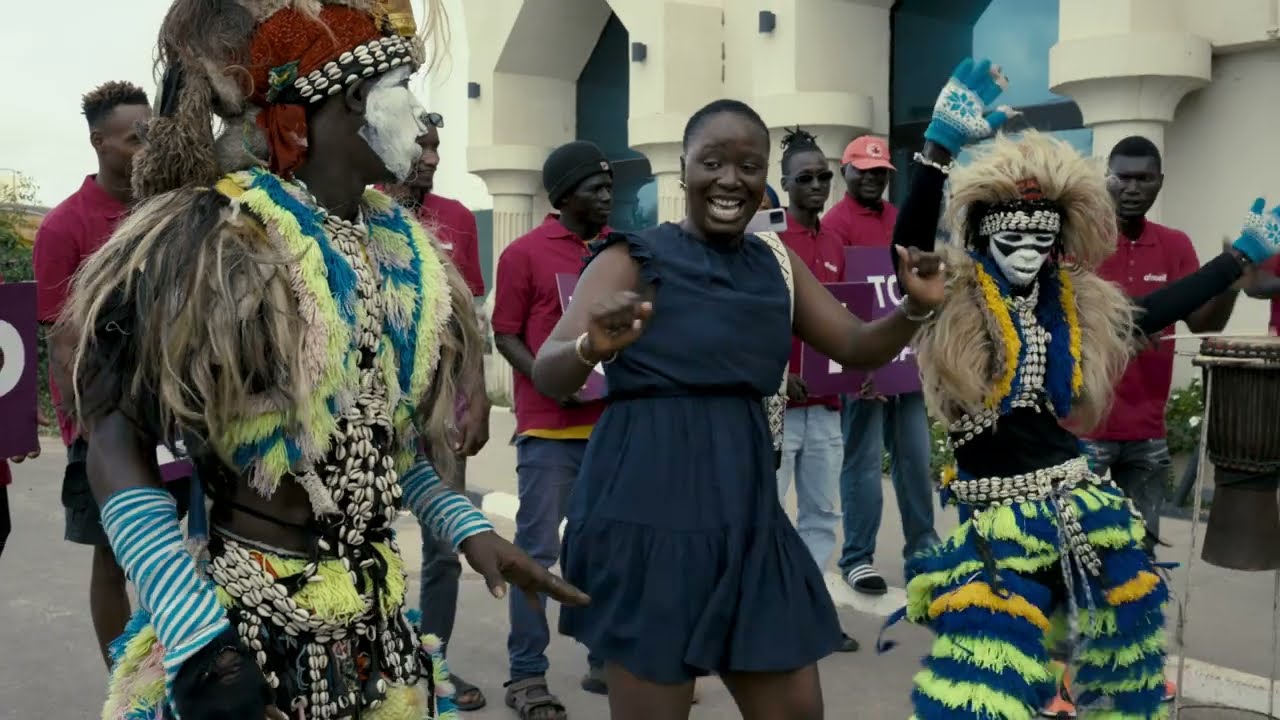 Pelumi Nubi among dancers in colourful costume at a street celebration.