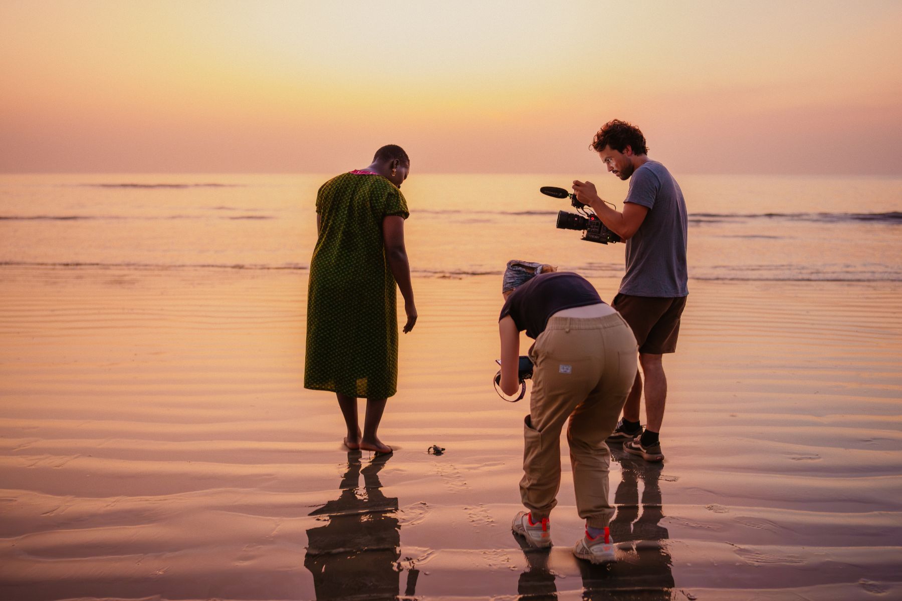 The crew filming on a beach at sunset.