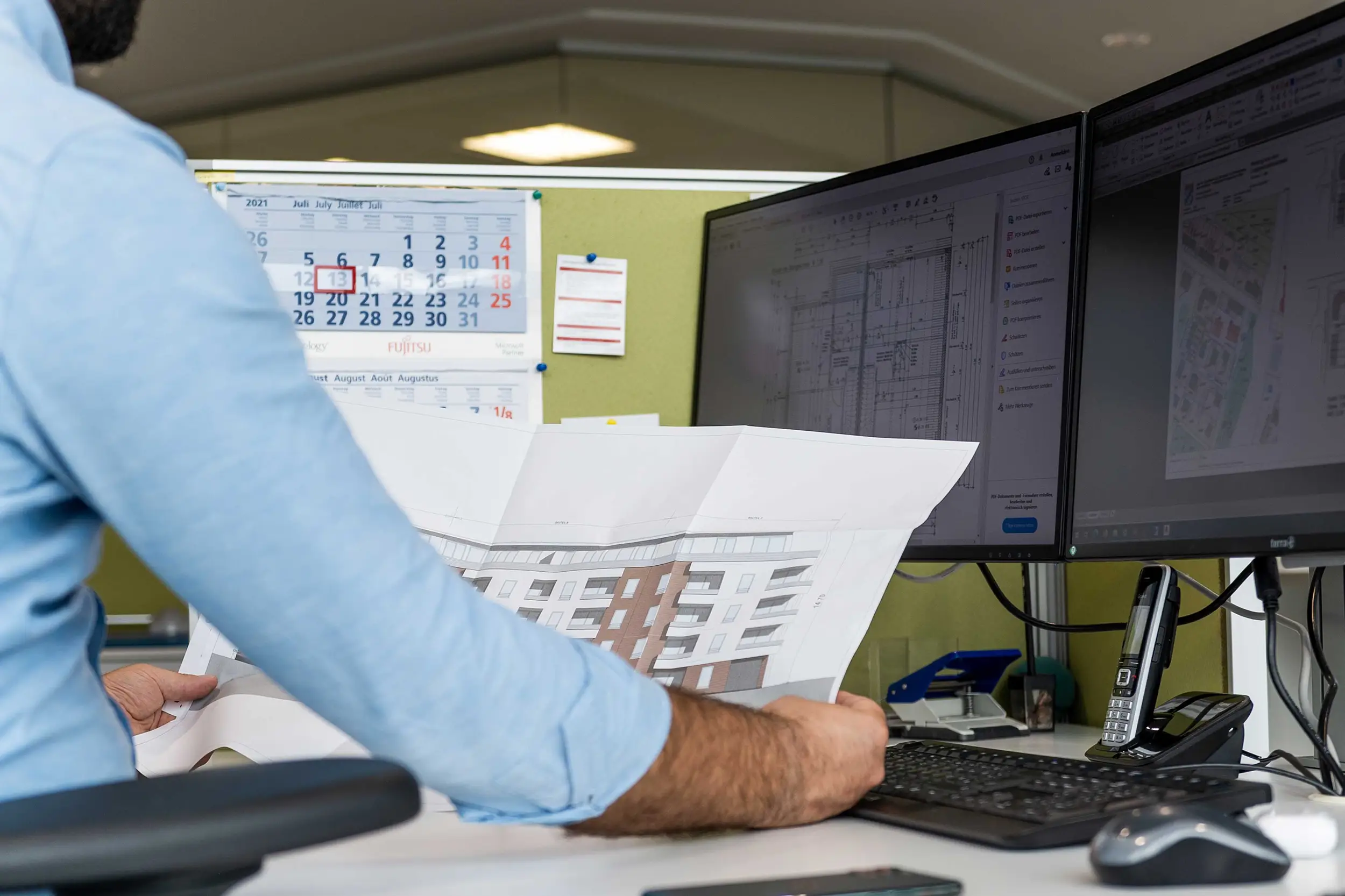 Mitarbeiter der May-Firmengruppe blicken gemeinsam auf einen Computer mit einer Grafik.