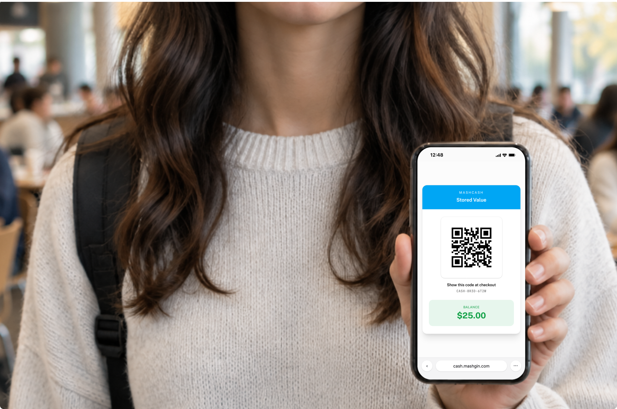 Woman in a cafeteria holding a phone that shows a MashCash digital card with a QR code and a $116.32 balance