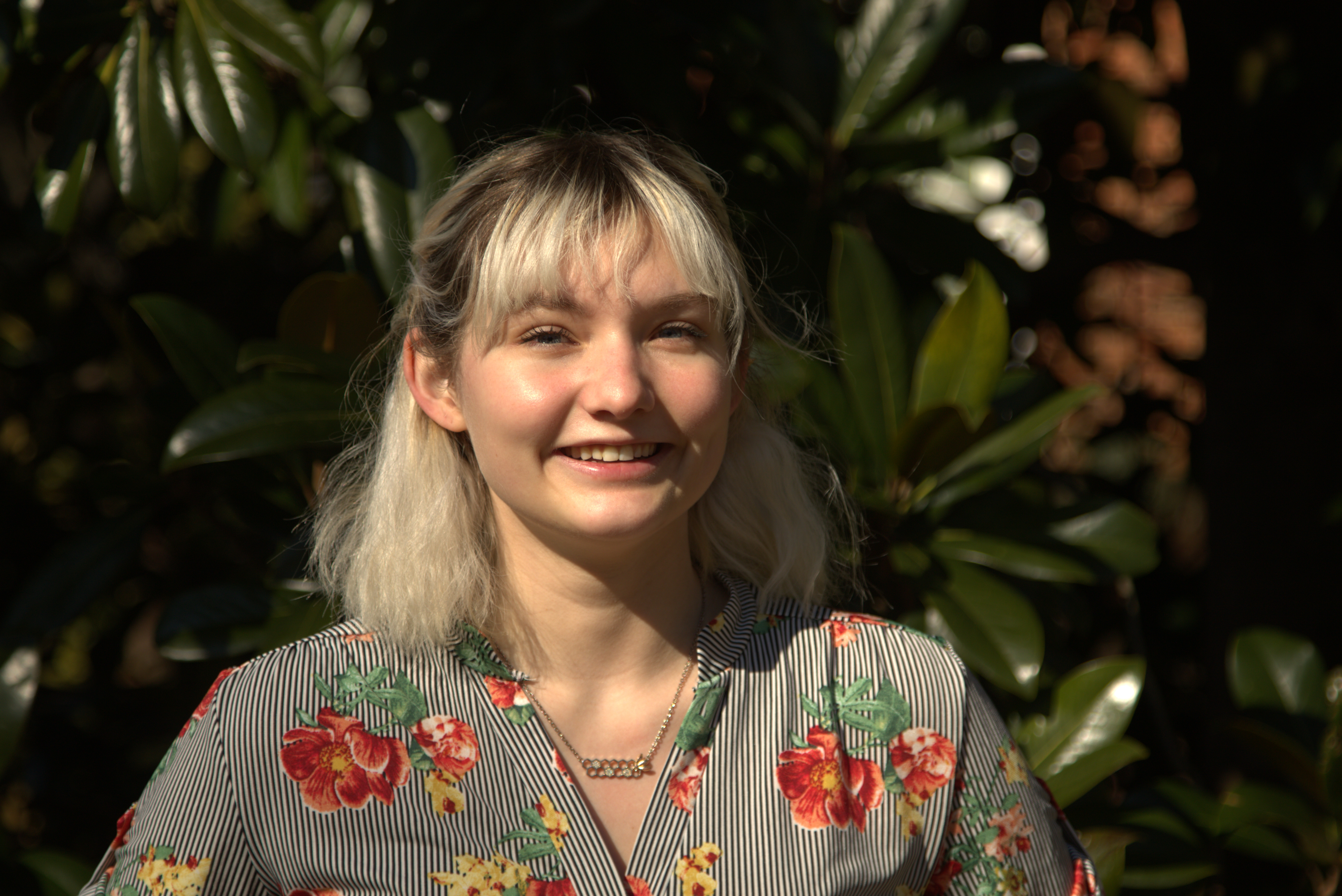 Photo of Madeleine, a young woman with blonde hair smiling in front of a mangrove
