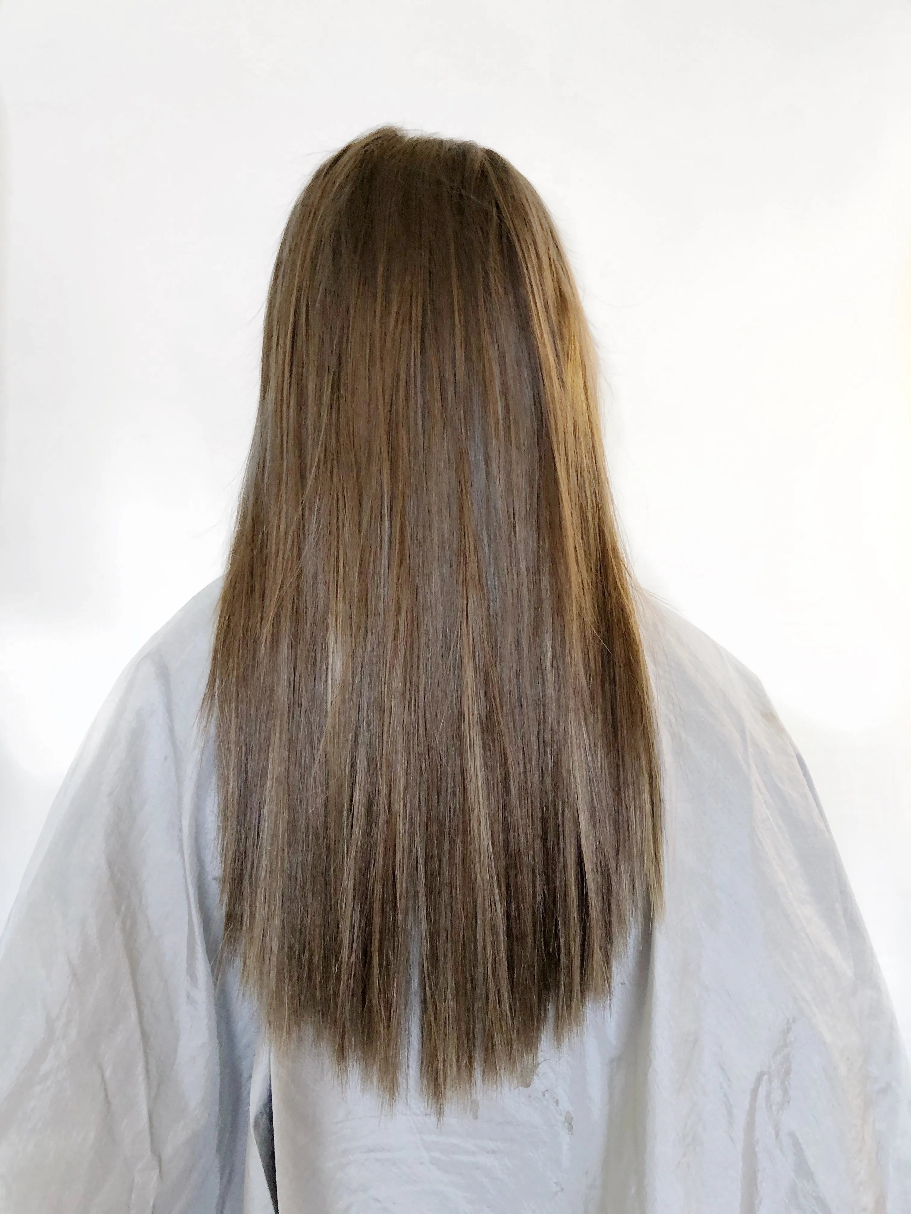 Back view of straight light brown hair with thin tapered ends before extensions