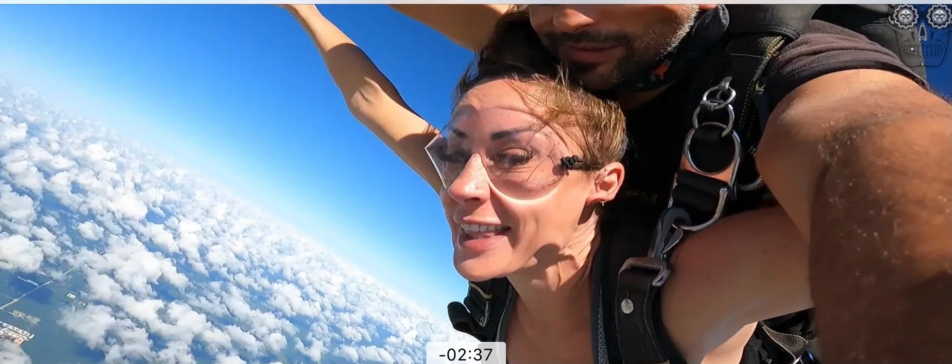 Tandem skydiver grinning above the clouds with her hair pulled back