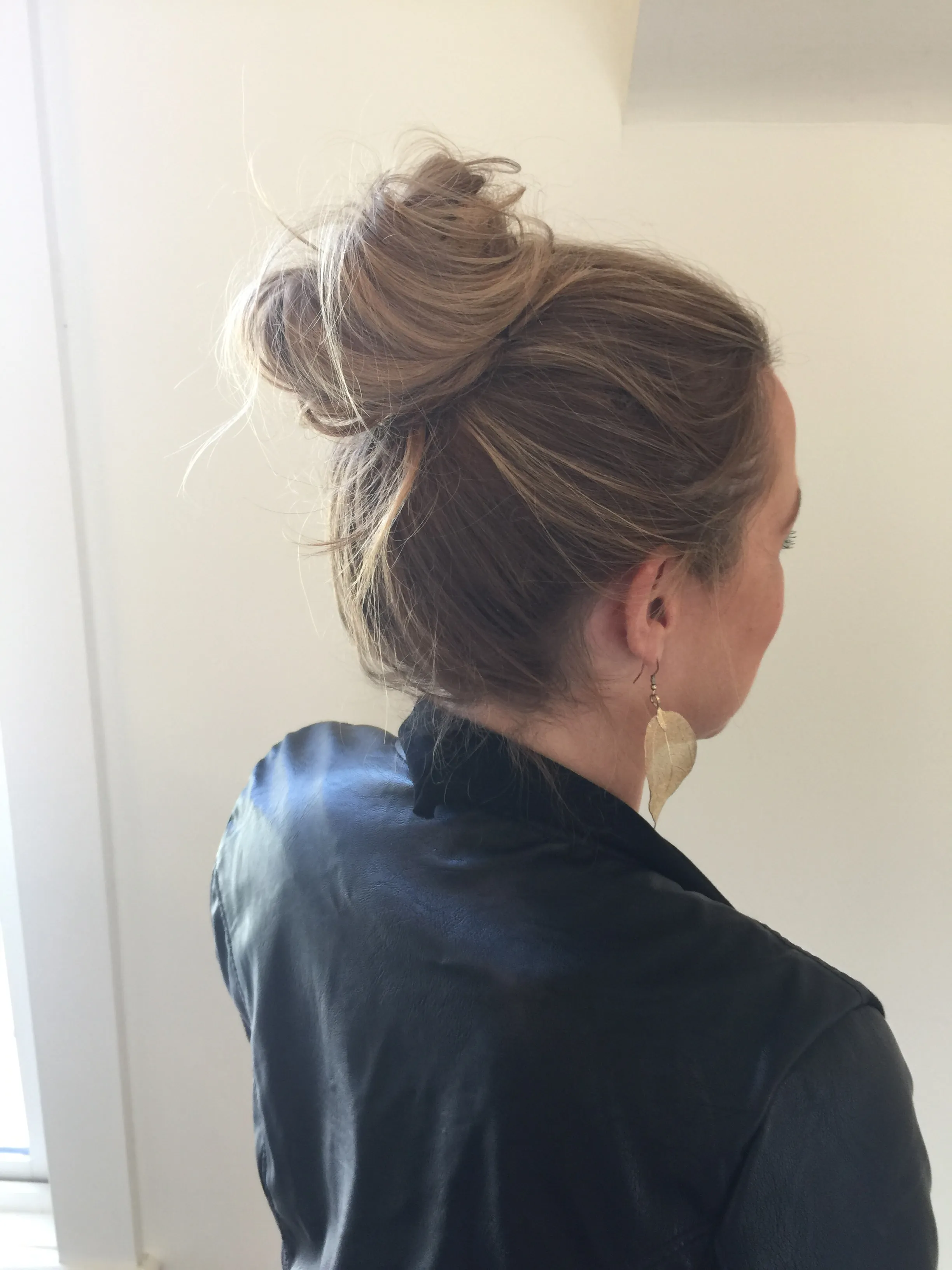 Loose low bun styled on blonde hair, worn with a satin robe