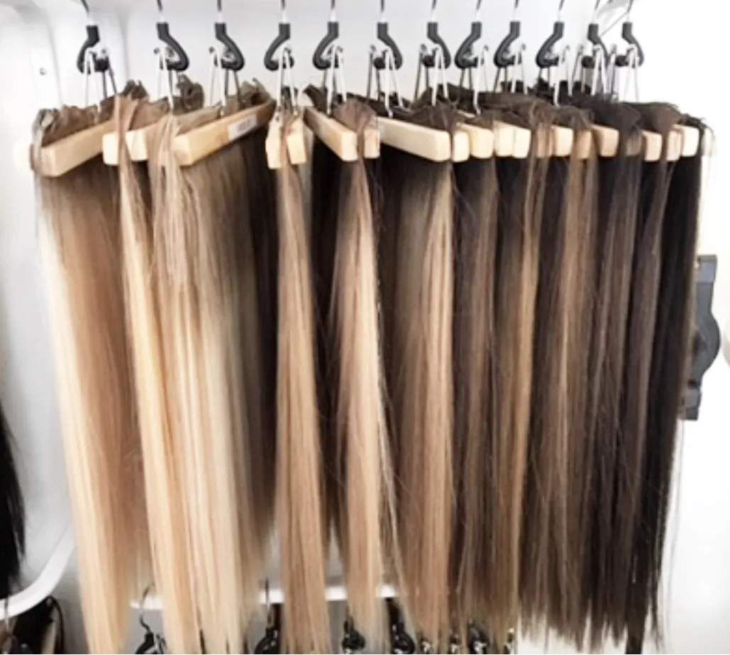 Hand-tied wefts hanging on wooden hangers in blonde and brunette shades