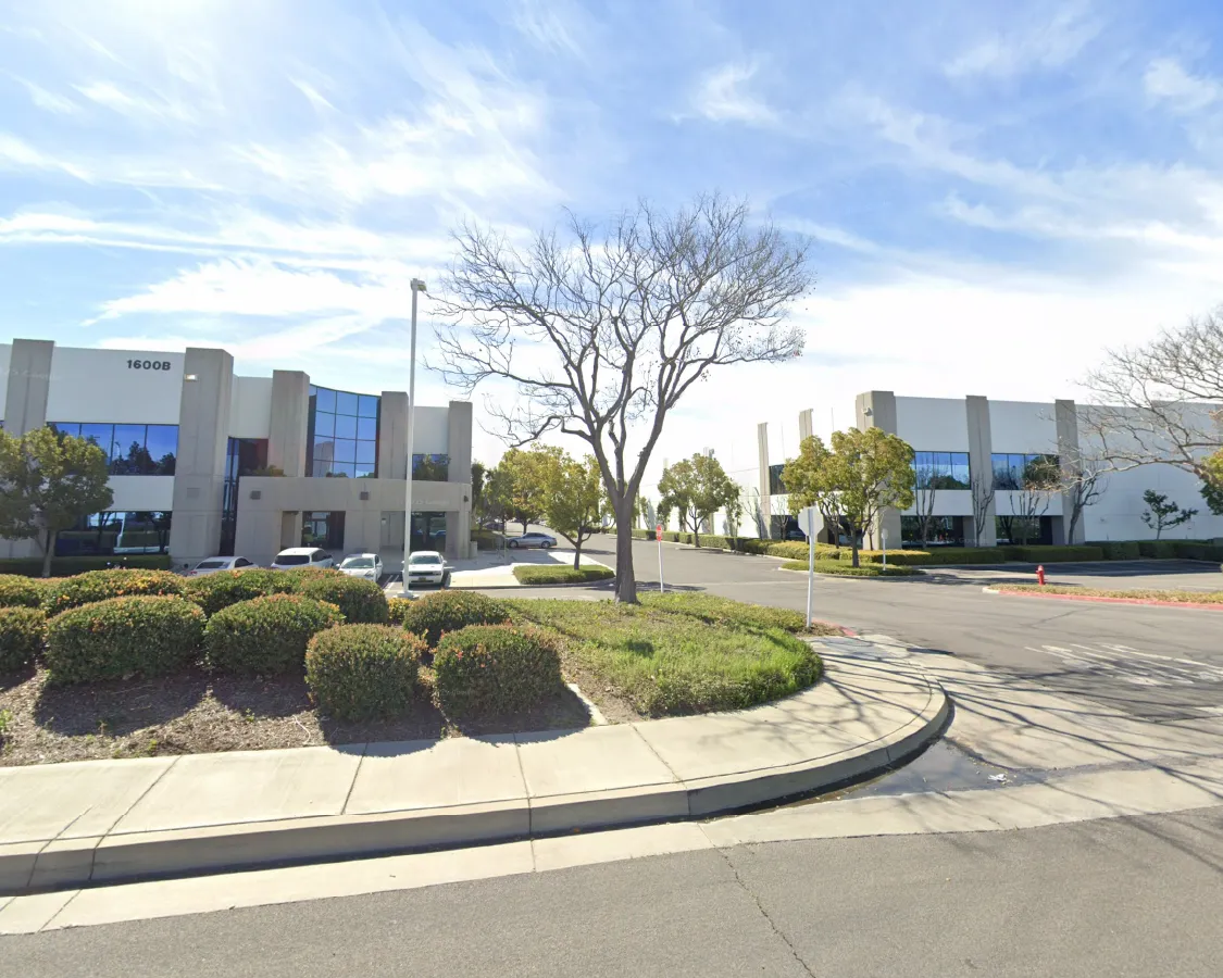 Corporate and production facility building is in a complex with professional modern buildings and hedges at entrance