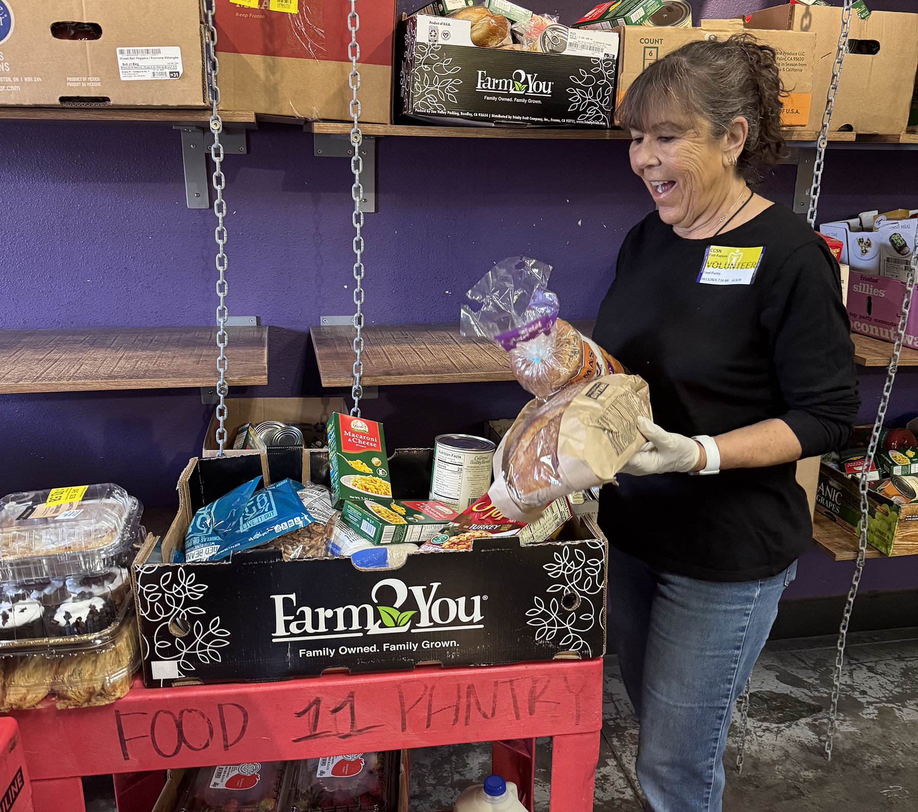 Senior volunteer wearing a mask and gloves packing fresh food items at a community food pantry