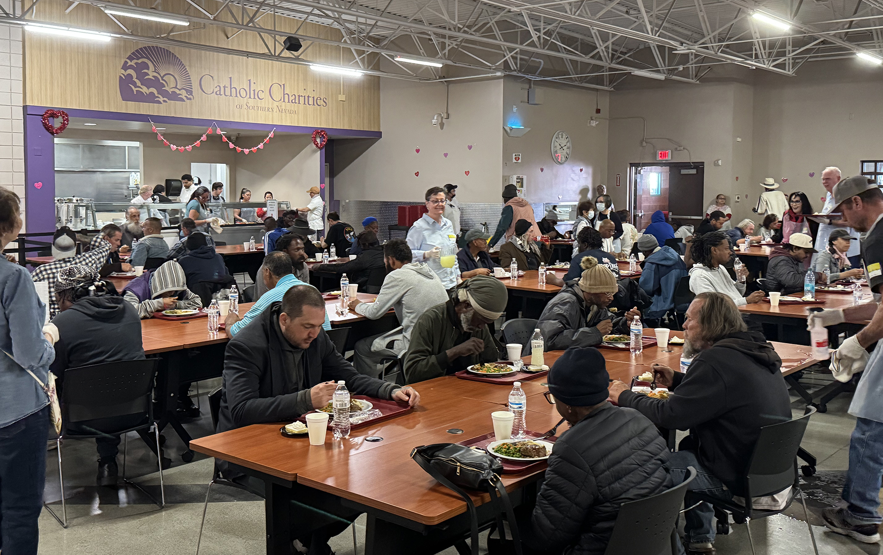 Dining hall full of volunteers serving food to people that are homeless or food insecure
