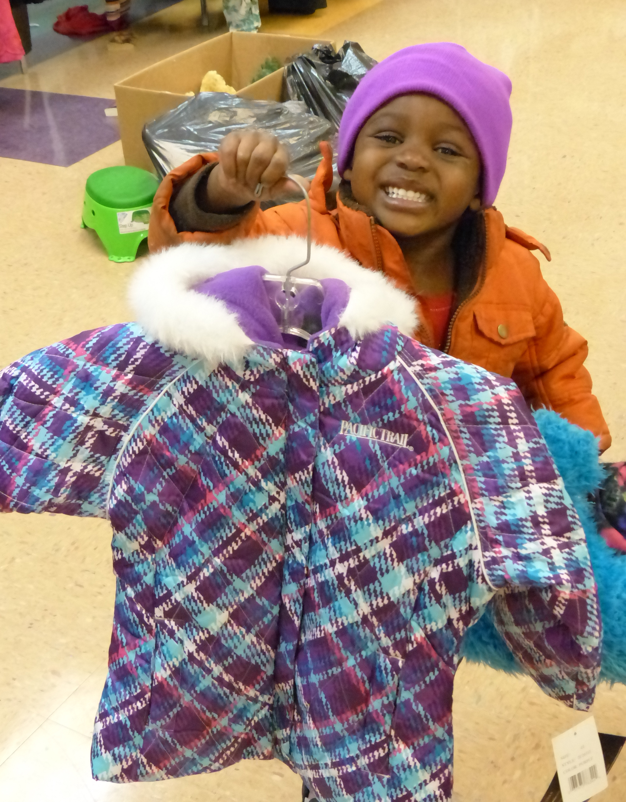 Woman wearing black glasses holding a baby boy and a winter jacket with a fur lined hood