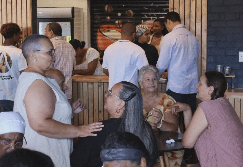 A group of people gathering in the café drinking coffee and tea.