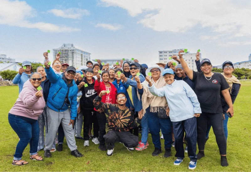 A group of seniors and volunteers cheering at the park.