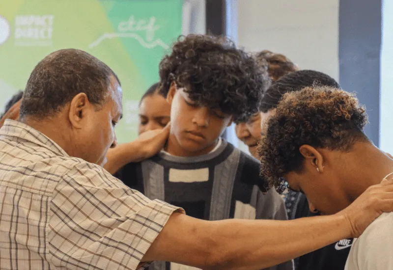 A pastor praying for two young boys during the service.