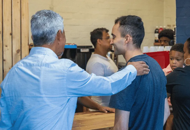 Two men greeting one another in the café while grabbing a cup of coffee.