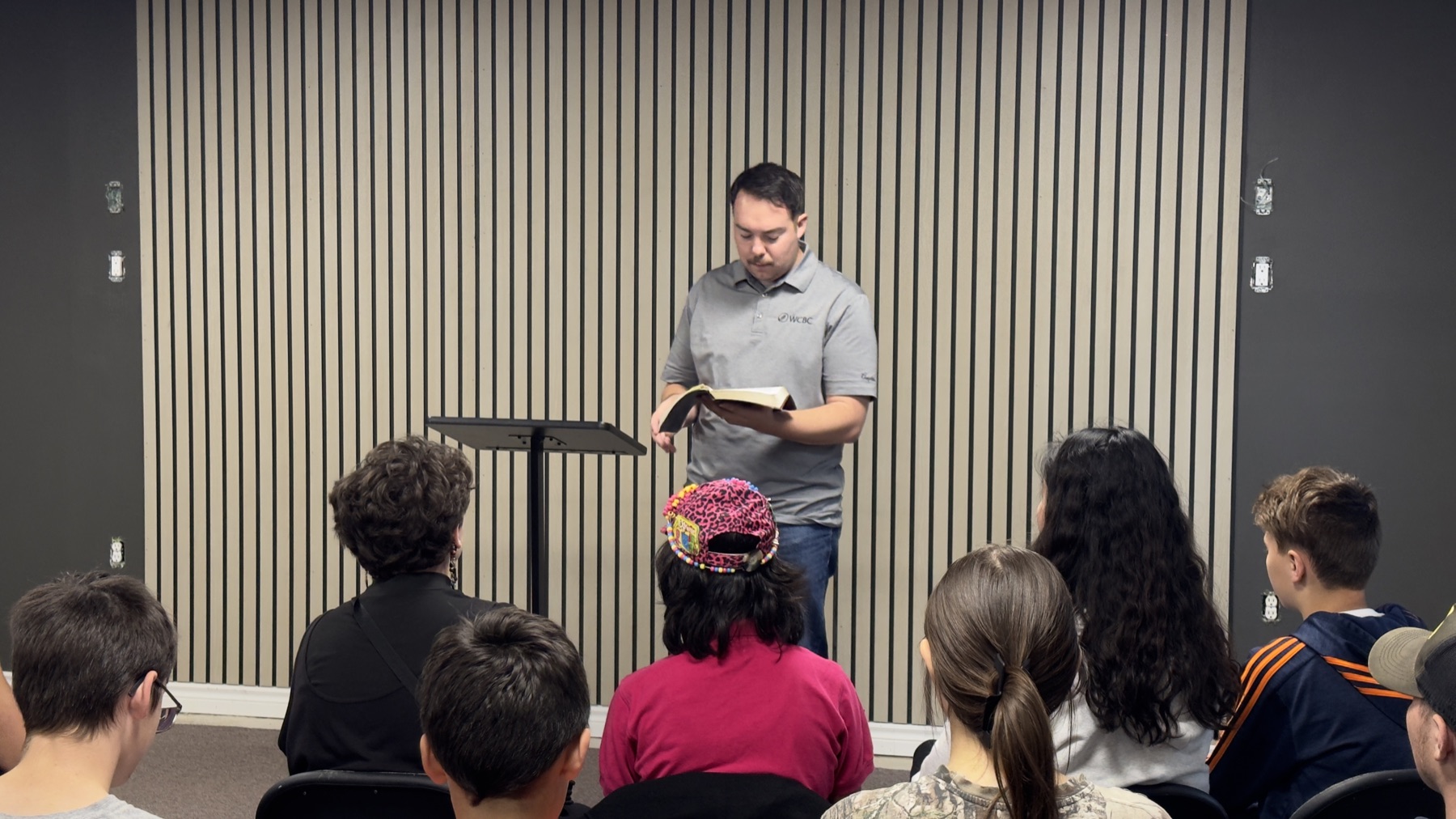 Pastor Austin Feere preaching from the Bible to a full room of teens