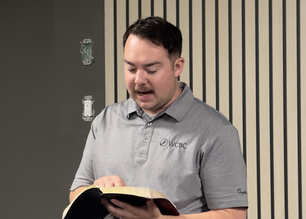 Pastor Austin Feere preaching from an open Bible at youth group