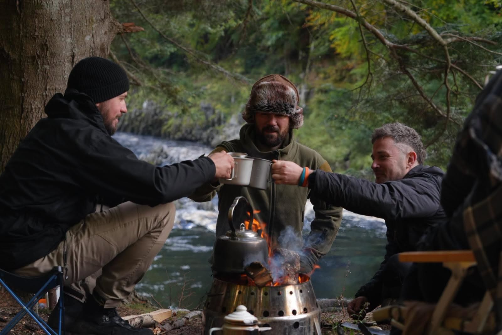 Steven Kelly, Jamie Frizzell and Sam Mouzer around a riverside fire during Highland Reckoning.