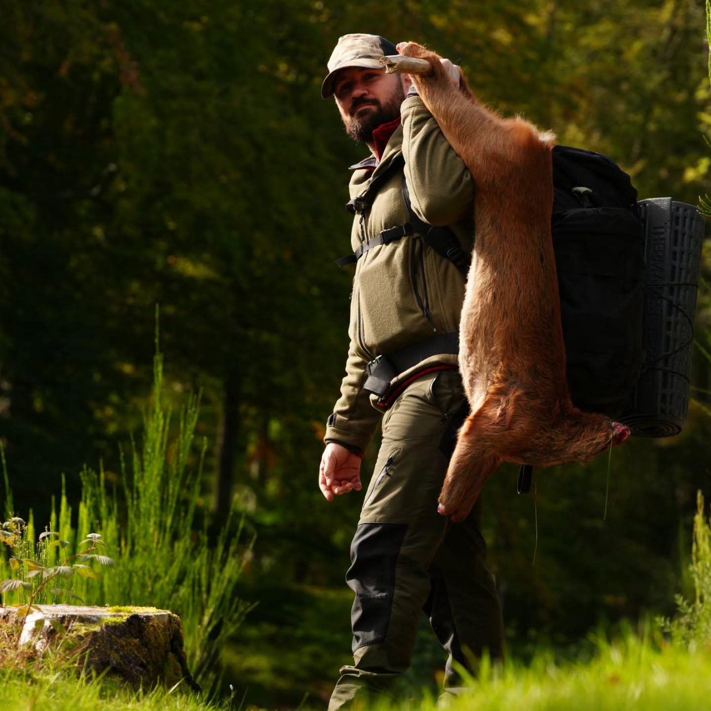 Steven Kelly carrying a deer through woodland during Highland Reckoning in Scotland.