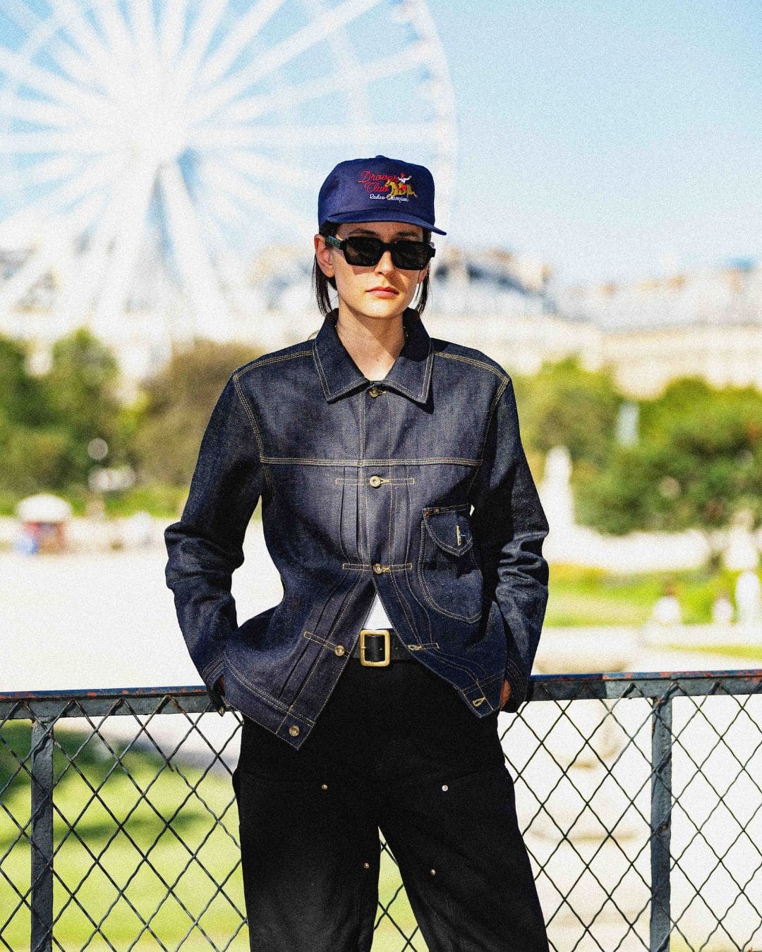 Modern Americana look featuring a raw denim trucker jacket and Drover Club 5 panel cap in front of a Ferris wheel