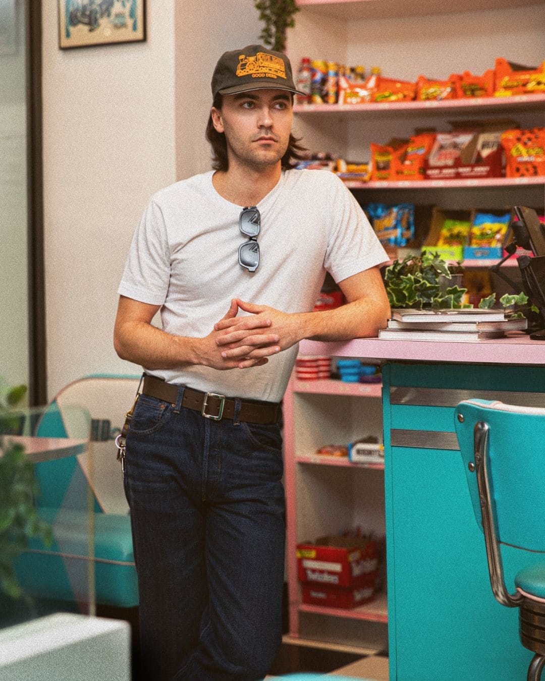 Modern Americana look with white tee, kaki and orange 5 panel cap and leather belt inside a retro American diner