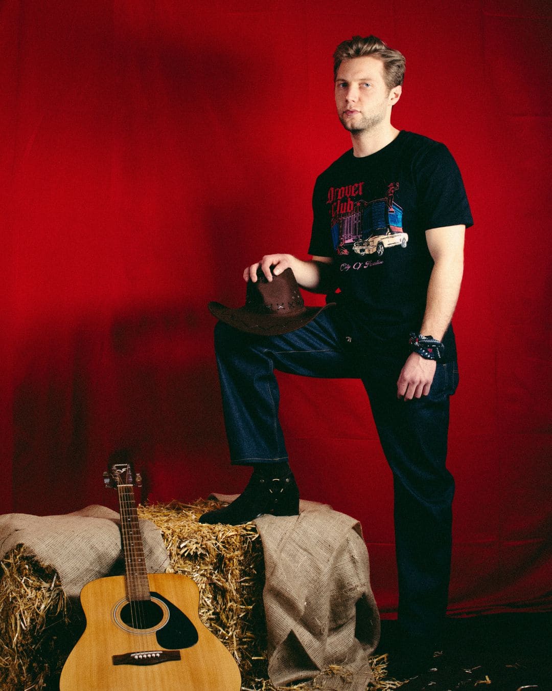 Western-inspired Modern Americana look with Drover Club graphic tee, cowboy hat, boots and acoustic guitar