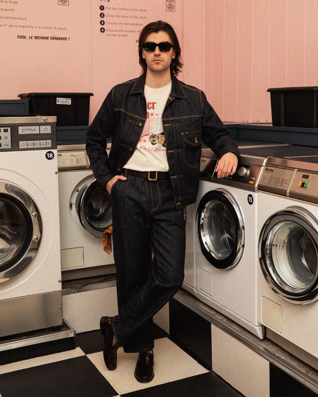 Modern Americana look in full raw denim with retro graphic tee and hand-burnished leather belt in an old-school laundromat