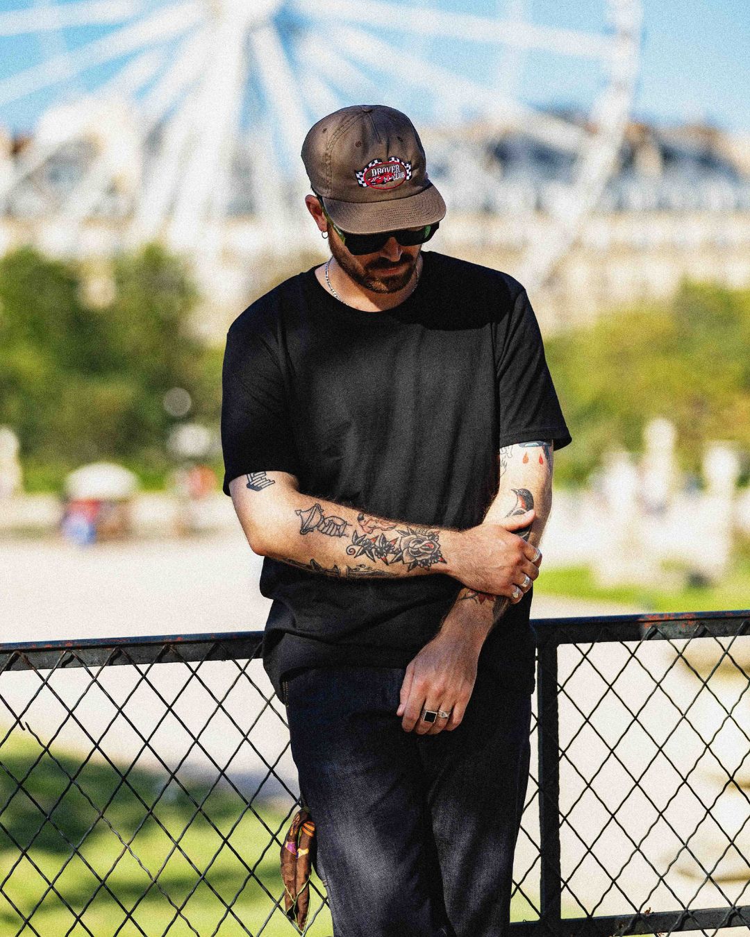 Men's Americana style with brown Motor Racing Club 5 Panel cap, black tee and denim jeans for a casual fairground look.