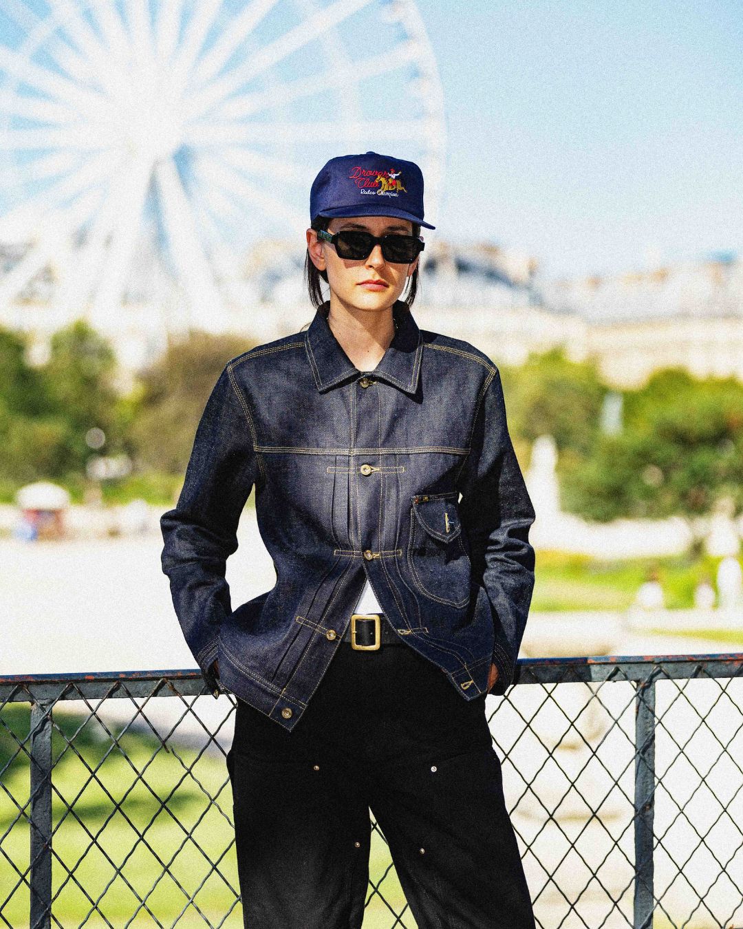 Woman wearing a navy Rodeo Champion 5 panel cap and raw denim jacket, urban Americana style.