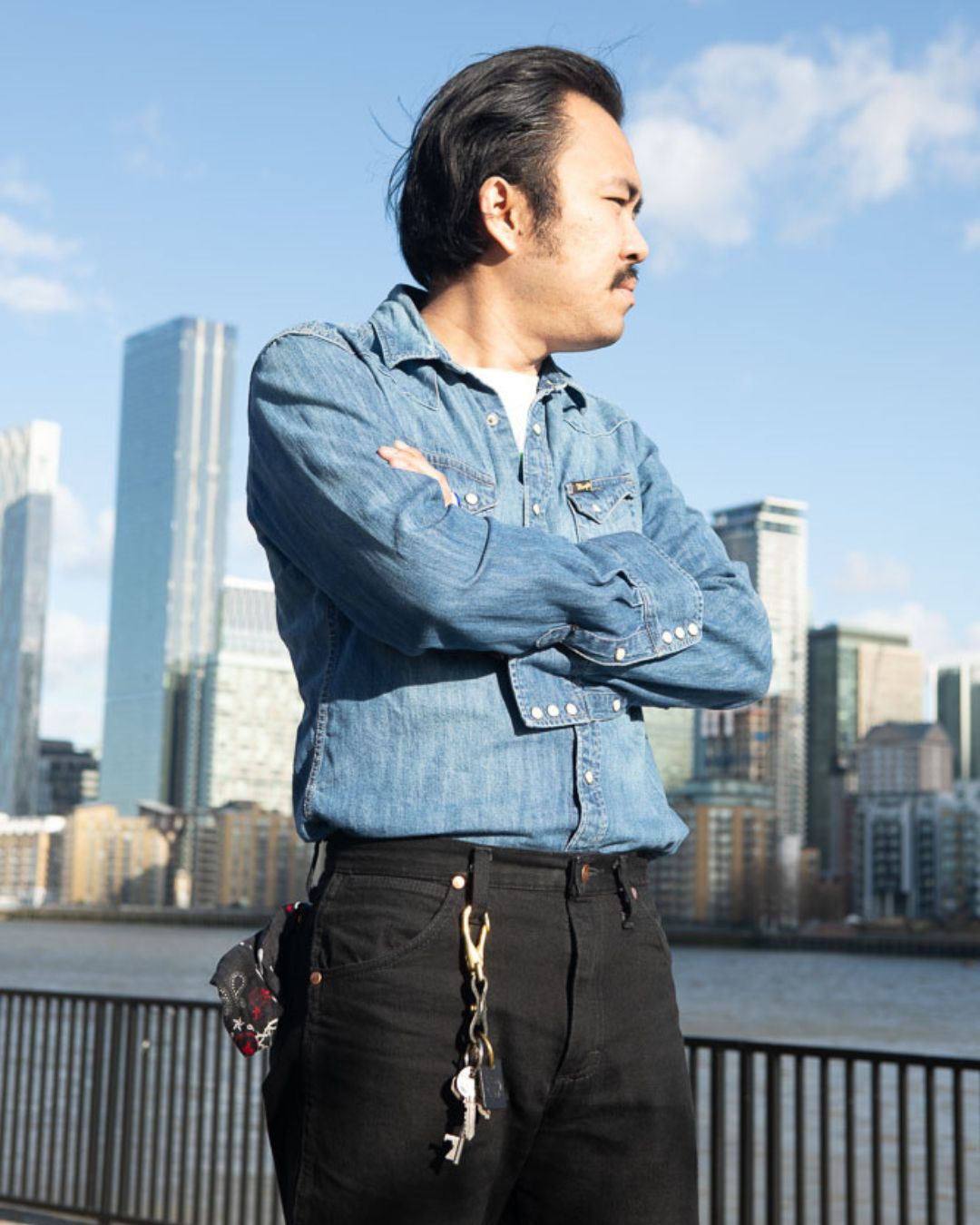 Man in denim shirt and black jeans wearing the Drover Club leather key clip, authentic Americana style.
