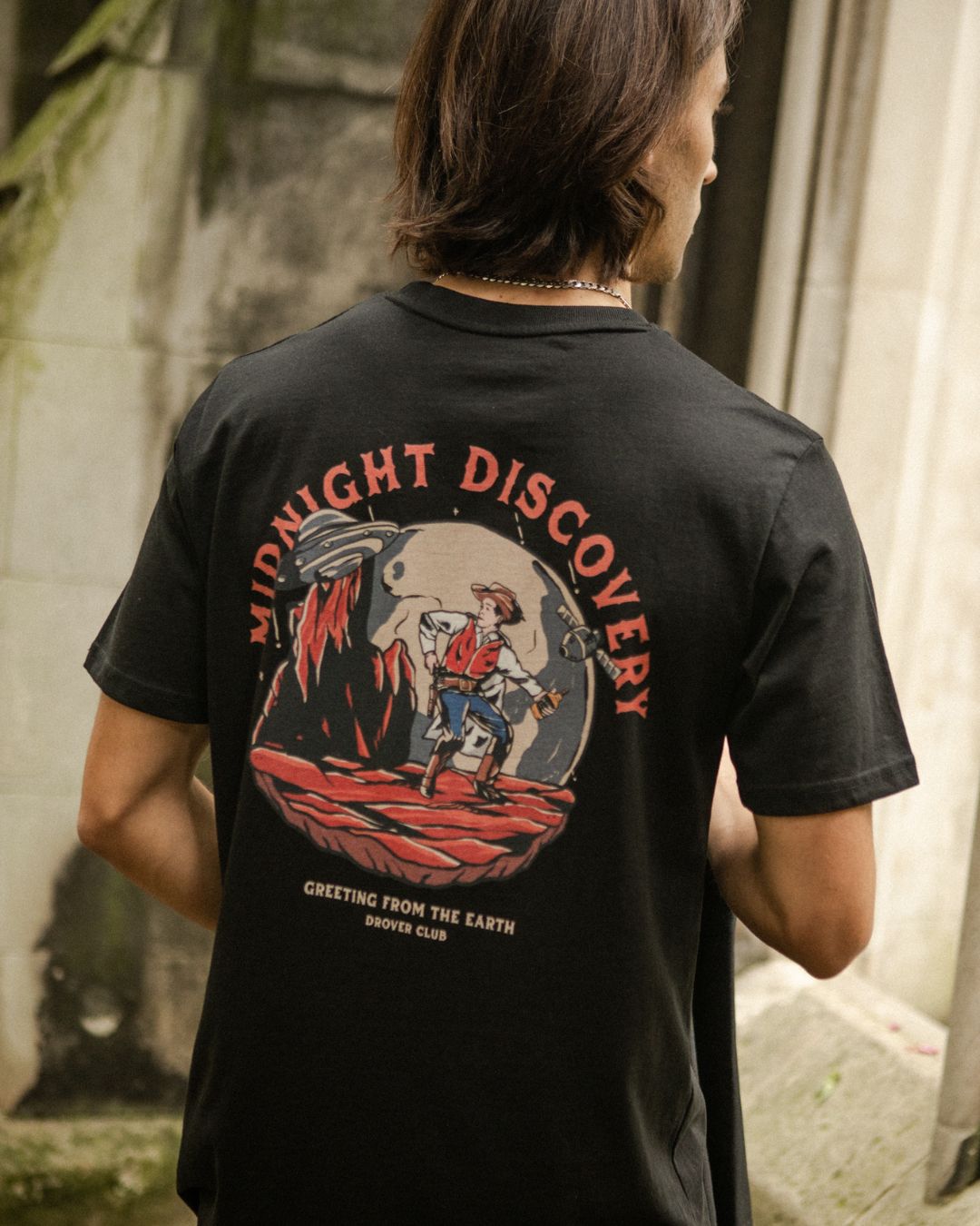 Man wearing the Drover Club Midnight Discovery Tee in black, featuring cowboy-inspired graphic back print.