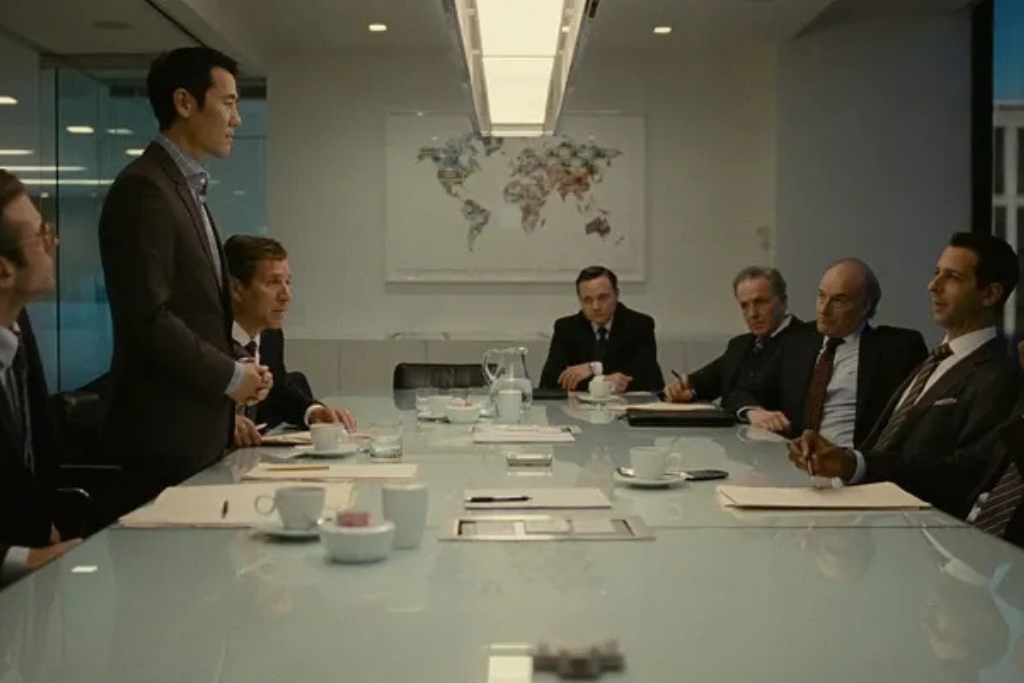 Executives in tailored suits during a high-level client presentation inside a modern boardroom.