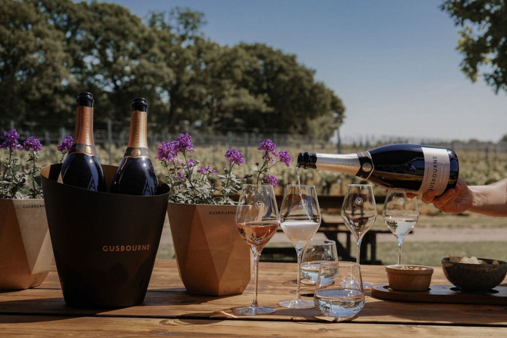 Wine tasting setup at Gusbourne Estate with sparkling wine, vineyard views and elegant countryside atmosphere.